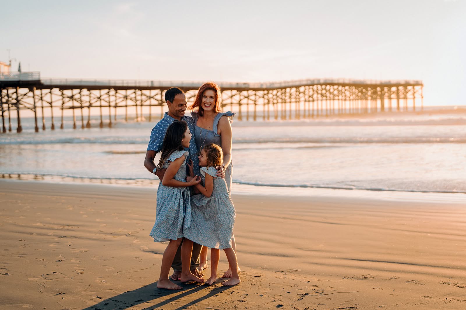Ashley Hanna-Morgan with her family on the beach at sunset, the Pacific Beach pier in San Diego behind them